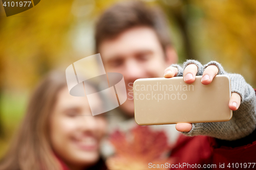Image of couple taking selfie by smartphone in autumn park