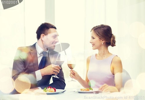 Image of couple with main course and red wine at restaurant