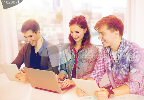 Image of three smiling students with laptop and tablet pc