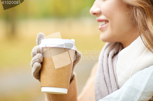 Image of close up of happy woman with coffee in autumn park