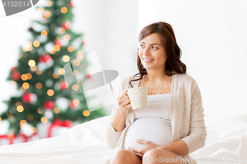Image of happy pregnant woman with tea cup at christmas