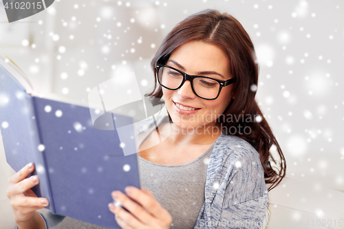 Image of young woman in glasses reading book at home