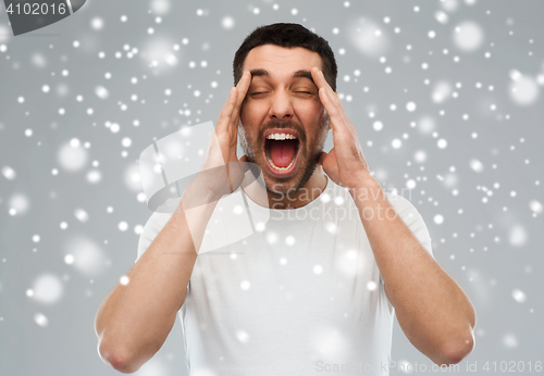 Image of crazy shouting man in t-shirt over snow background