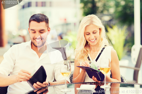 Image of happy couple with wallet paying bill at restaurant