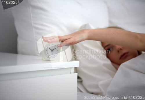 Image of close up of woman with alarm clock in bed at home