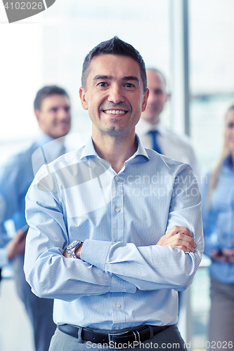 Image of smiling businessman with colleagues in office