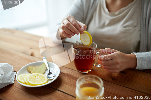 Image of close up of woman adding lemon to tea cup