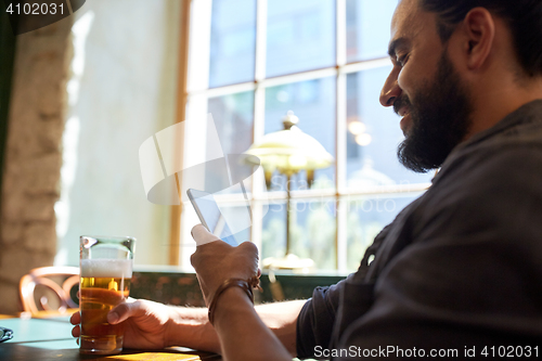 Image of close up of man with smartphone and beer at pub