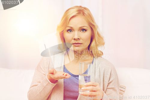 Image of woman with medicine and water glass at home