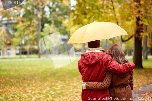 Image of happy couple with umbrella walking in autumn park