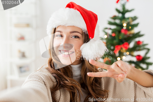 Image of happy woman taking selfie over christmas tree