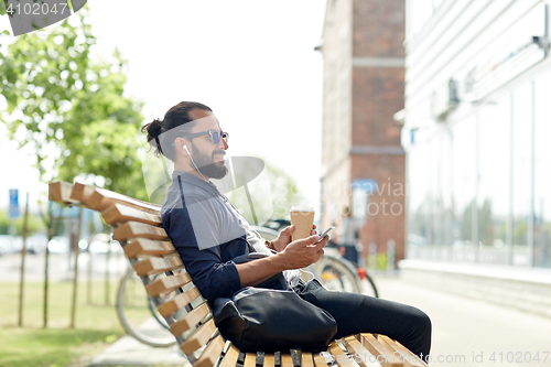 Image of man with earphones and smartphone drinking coffee