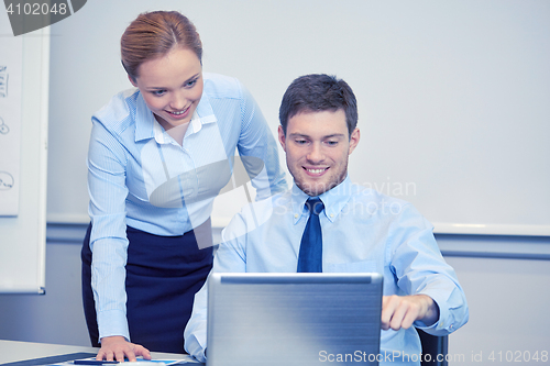 Image of smiling businesspeople with laptop in office