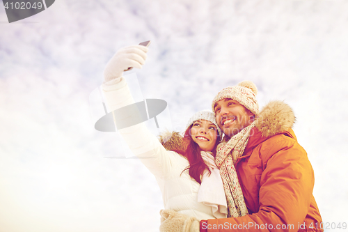 Image of happy couple taking selfie by smartphone in winter