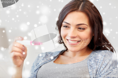 Image of happy woman looking at home pregnancy test