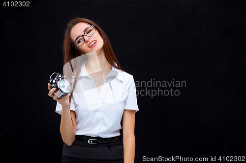 Image of The young business woman with alarm clock on black background
