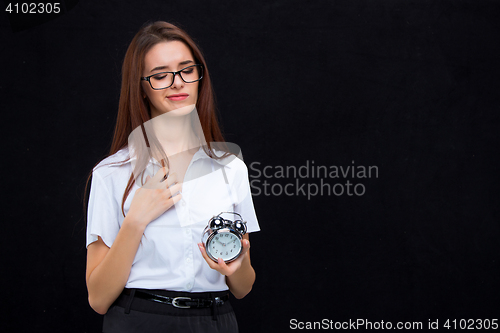 Image of The young business woman with alarm clock on black background