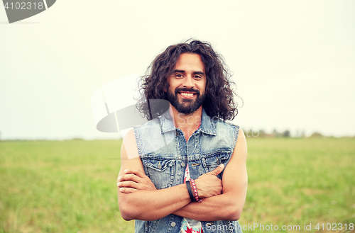 Image of smiling young hippie man on green field