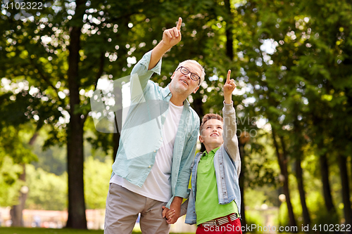 Image of grandfather and boy pointing up at summer park