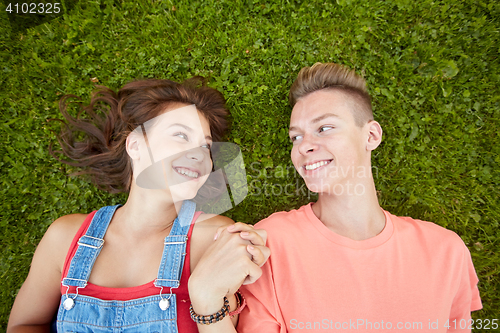 Image of happy teenage couple lying on grass at summer