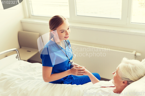 Image of doctor or nurse visiting senior woman at hospital