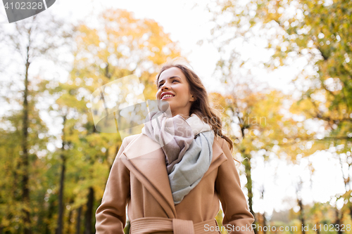 Image of beautiful happy young woman walking in autumn park