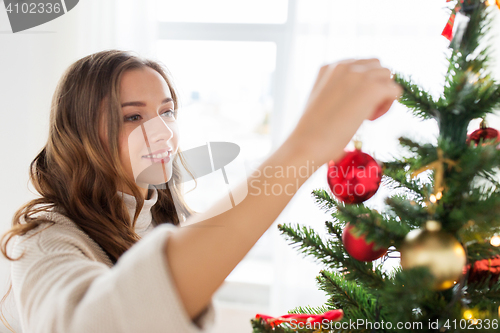 Image of happy young woman decorating christmas tree