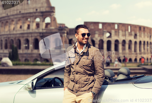 Image of happy man near cabriolet car over coliseum
