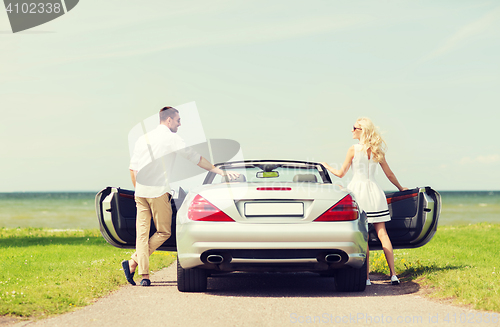 Image of happy man and woman near cabriolet car at sea