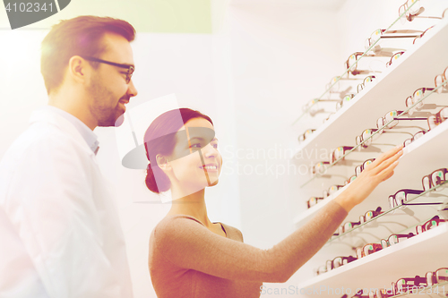 Image of woman showing glasses to optician at optics store