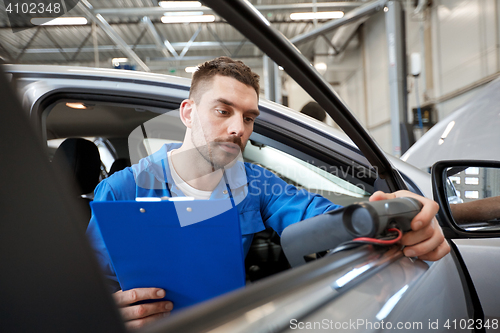 Image of mechanic man with diagnostic scanner at car shop