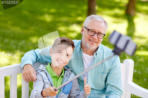 Image of old man and boy taking selfie by smartphone