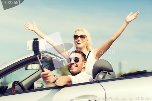 Image of happy couple in car taking selfie with smartphone