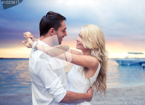 Image of happy couple hugging over sunset beach background
