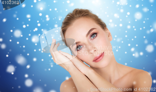 Image of beautiful young woman face and hands over snow