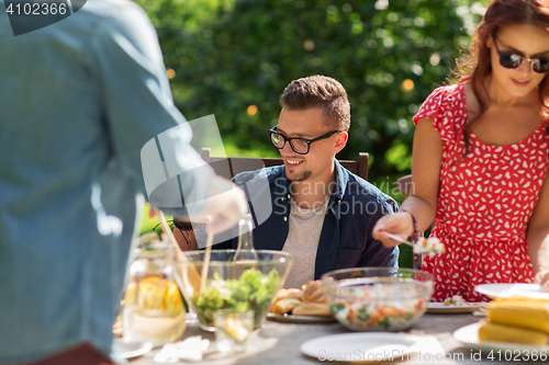 Image of happy friends having dinner at summer garden party