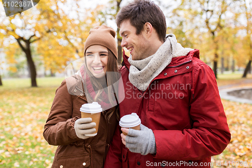 Image of happy couple with coffee walking in autumn park