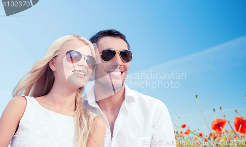 Image of happy couple in shades over poppy field background