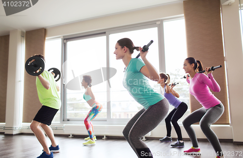 Image of group of people exercising with barbell in gym