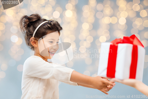 Image of smiling little girl giving or receiving present