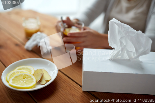 Image of ill woman drinking tea with lemon and ginger