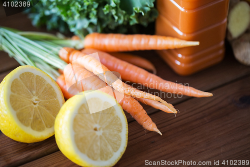 Image of close up of carrot, lemon and bottle with juice