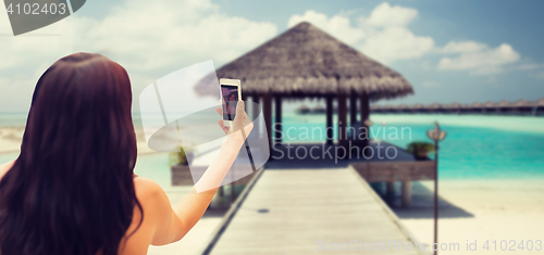 Image of young woman taking selfie with smartphone