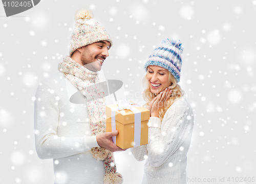 Image of smiling couple in winter clothes with gift box