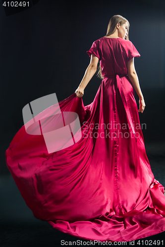 Image of Back view of young blonde woman in bright pink dress