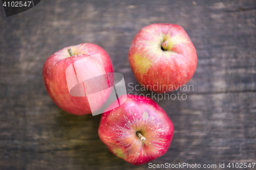 Image of Three red apples on wooden table