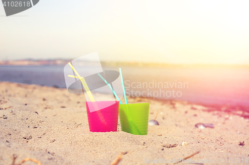 Image of Colorful drink cups in the sand