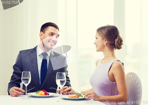 Image of smiling couple eating main course at restaurant