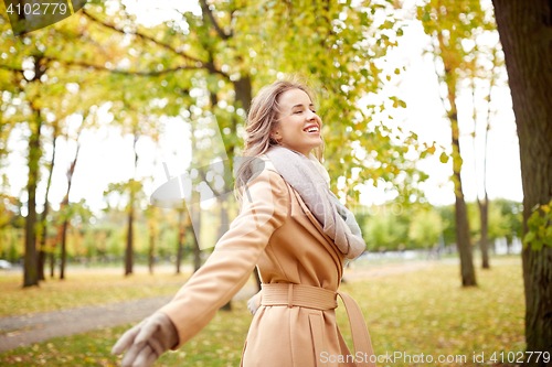 Image of beautiful happy young woman walking in autumn park