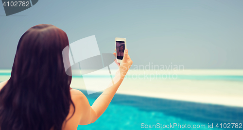 Image of young woman taking selfie with smartphone